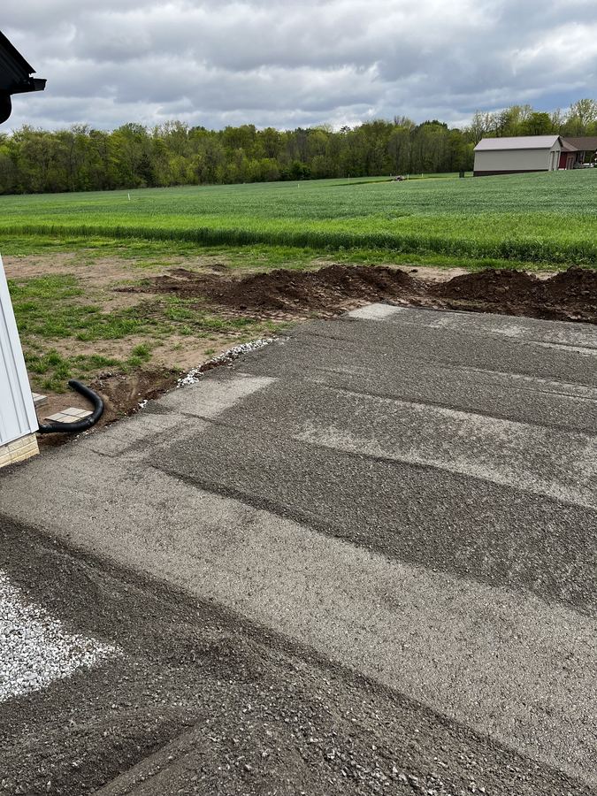 Graded driveway base prepped alongside a house