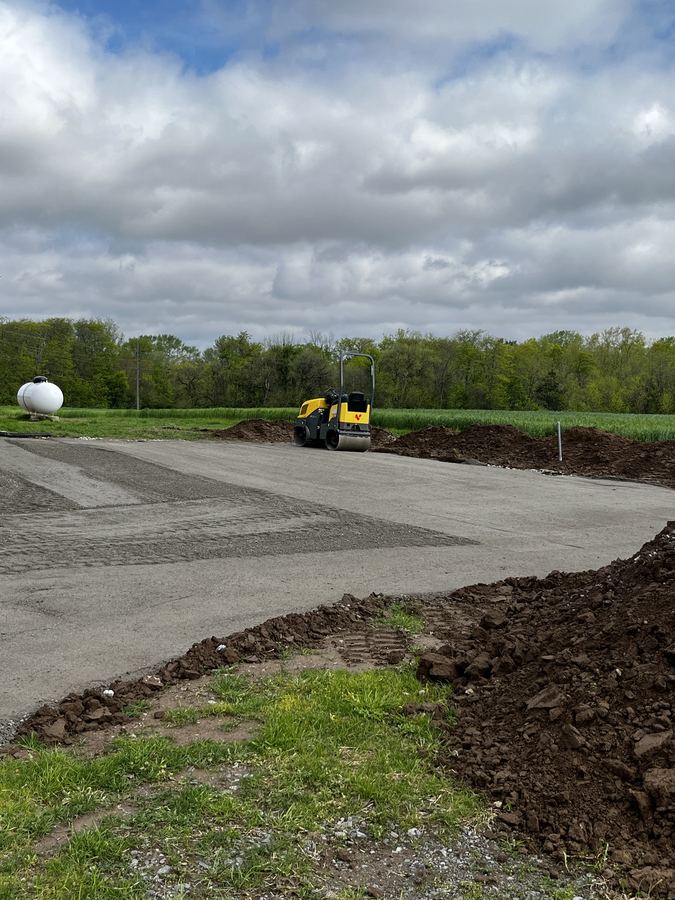 Roller compactor packing a new gravel driveway base